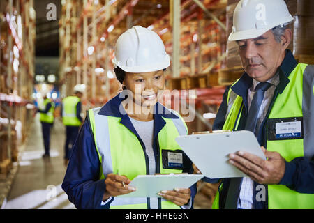 Manager e lavoratore con appunti riunione nel magazzino di distribuzione Foto Stock