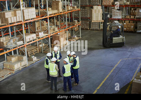 I lavoratori riuniti in un cerchio nel magazzino di distribuzione Foto Stock