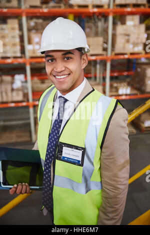 Ritratto sorridente manager con tavoletta digitale nel magazzino di distribuzione Foto Stock