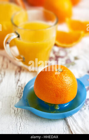 Centrifuga in plastica con un bicchiere di succo d'arancia fresco su bianco rustico sfondo di legno Foto Stock