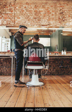 Parrucchiere dando un taglio di capelli a client maschio al salone. L'uomo getting haircut al Barber shop. Foto Stock