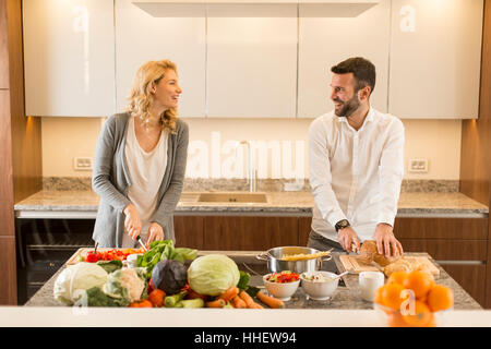 Giovani amare giovane preparando gustosi pasti in una moderna cucina Foto Stock