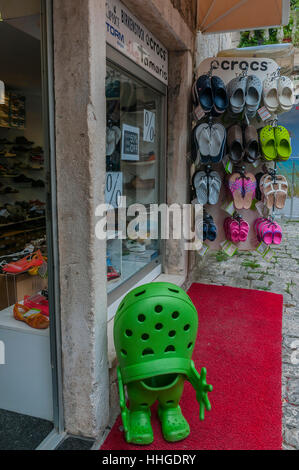Al di fuori di una calzatura negozio in Trogir La città antica è un luminoso verde coccodrillo di gomma scarpa con mani e piedi per fare un display umoristico. Foto Stock