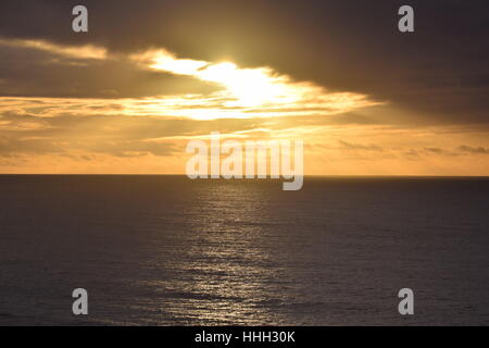 Sunset spiata attraverso le nuvole, scintillante luce sull'oceano pacifico Foto Stock