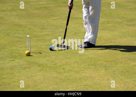 Close-up di un uomo che colpisce una sfera per croquet con un mazzuolo. Foto Stock