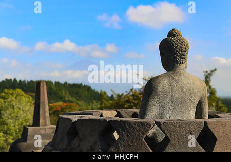 Una statua di Buddha si affaccia verso il Monte Merapi dal tempio di Borobudur in Magelang, Giava centrale, Indonesia. Foto Stock