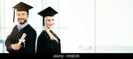 Laurea - happy studenti indossando camice e cappuccio. spazio copia Foto Stock