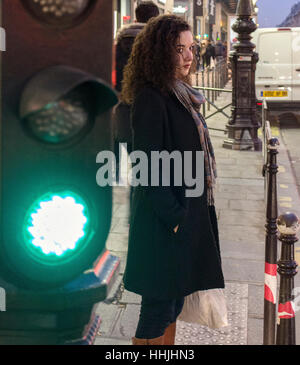 La donna in attesa di attraversare la strada. Il semaforo verde è accanto a lei. Foto Stock