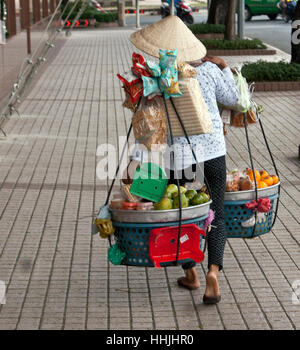 La frutta e la verdura venditore camminando sulla strada, a Saigon, Vietnam Foto Stock