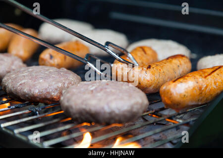 Salsicce e hamburger di essere cucinati su un barbecue Foto Stock
