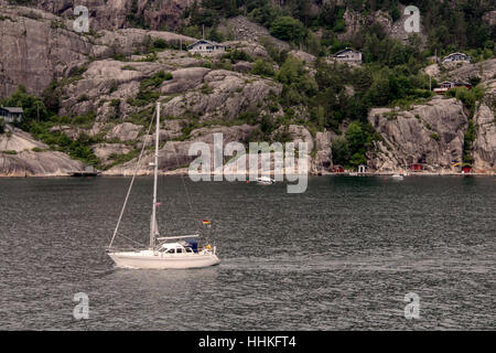 Barca a vela vela sul suo motore in un fiordo norvegese Foto Stock