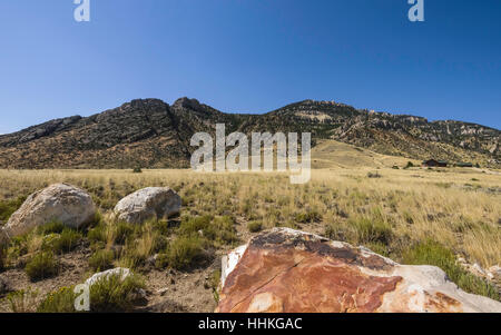 Il paesaggio arido di prateria in tarda estate con vista delle colline ai piedi delle Montagne Rocciose e isolato ranch house in estate. Foto Stock