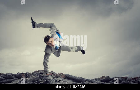 Giovane imprenditore allegro facendo handstand sul bordo di roccia Foto Stock