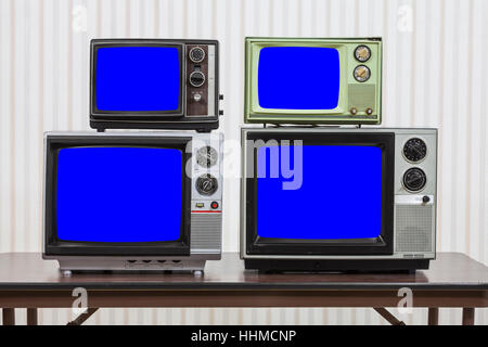 Quattro televisori vintage sulla tavola con chroma key schermate blu. Foto Stock