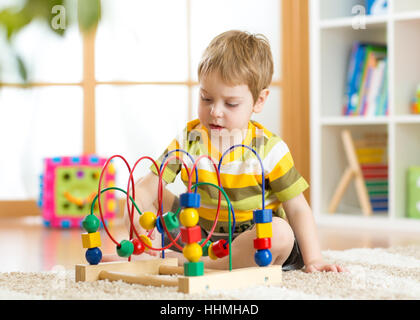 Kid boy gioca con una logica multicolore giocattolo in vivaio Foto Stock