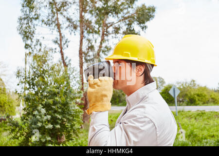 Operaio edile di bere il caffè al sito in costruzione Foto Stock