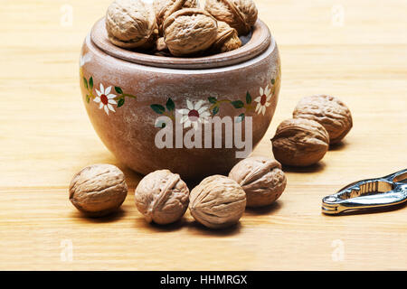 Noci (Juglans regia) in un recipiente di ceramica su una tavola di legno Foto Stock