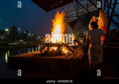 La cremazione di un corpo morto a combustione ghats di notte, il tempio di Pashupatinath, rive del fiume Bagmati, Kathmandu Foto Stock