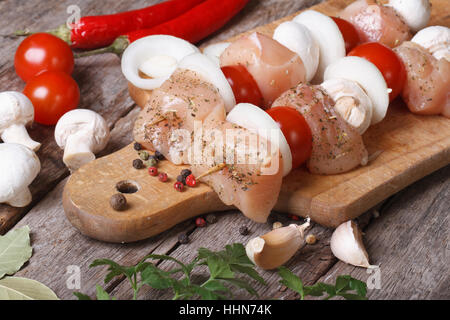 Il pollo crudo shish kebab con funghi, pomodori e cipolle su un tagliere close up orizzontale Foto Stock
