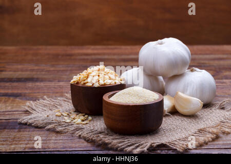 4 spicchi di aglio, lampadina, fiocchi e polvere sul vecchio pannello di legno Foto Stock