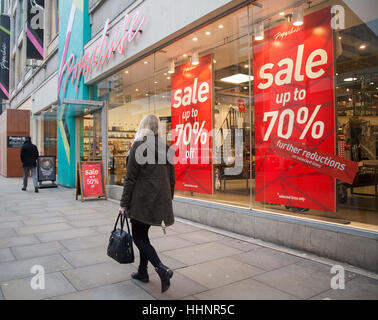 Donna che passa davanti al negozio di cartoleria Paperchase negozi 'fino al 70% di sconto' sconti poster, ulteriori riduzioni a Manchester, Regno Unito Foto Stock