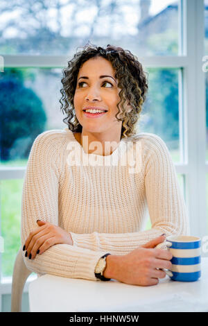Curioso donna seduta al tavolo azienda tazza da caffè