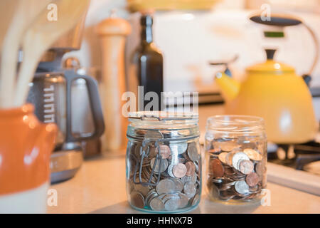 Vasi di monete sul banco di cucina Foto Stock