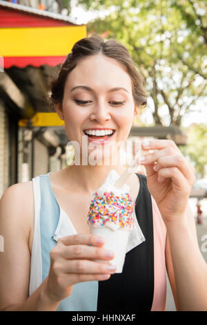 Donna Thai a mangiare il gelato in città Foto Stock