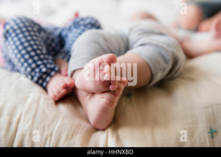 Piedi di soggetti di razza caucasica twin baby ragazze posa sul letto Foto Stock