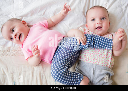 Twin caucasica baby ragazze giocando sul letto Foto Stock