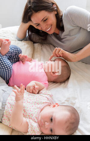 Madre caucasica toccando il naso della bimba sul letto Foto Stock