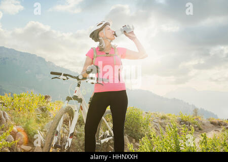 La donna caucasica con mountain bike di bere dalla bottiglia Foto Stock