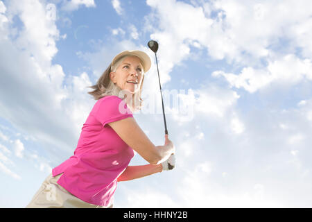 La donna caucasica swinging golf club Foto Stock