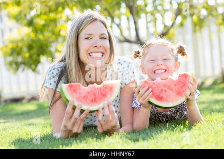 Caucasian madre e figlia in posa erba mangiando anguria Foto Stock