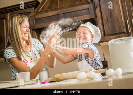 Caucasian madre e figlia avente cibo lotta con farina Foto Stock