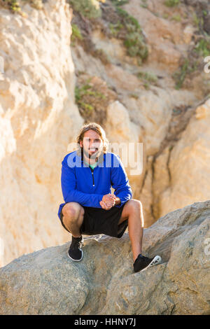 Uomo caucasico accovacciato sulla formazione di roccia Foto Stock