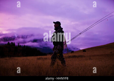Uomo caucasico a piedi e il trasporto di canne da pesca Foto Stock