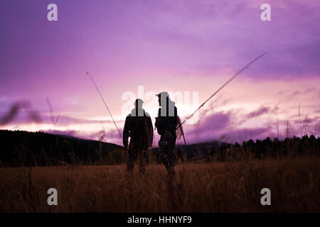 Uomini caucasici che porta canne da pesca Foto Stock