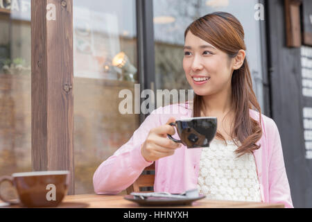 Donna seduta sulla sedia e un caffè Foto Stock