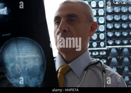 Medico di origine ispanica esaminando a raggi x del cranio Foto Stock