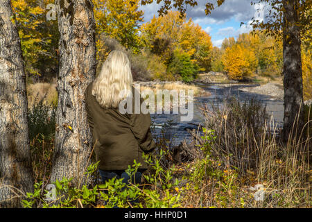 La donna caucasica appoggiata su albero vicino al fiume Foto Stock