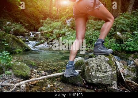 Gambe di donna caucasica escursionismo su fiume Foto Stock