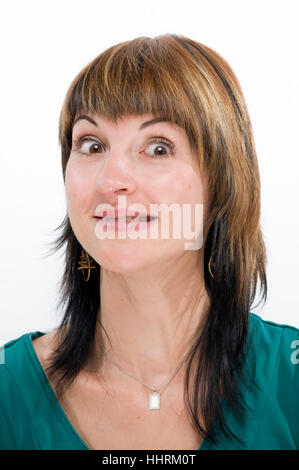 Testa ritratto di una giovane donna bruna contro uno sfondo bianco dubiously scary guardando nella telecamera. Foto Stock