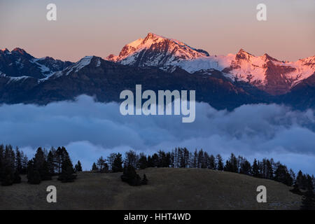 Tramonto in inverno sul Parco Nazionale degli Ecrins picchi di montagna (Chaillol, Queyrel, Tourond) sollevamento sopra le nuvole. Champsaur Valley. Hautes Alpes, Southe Foto Stock