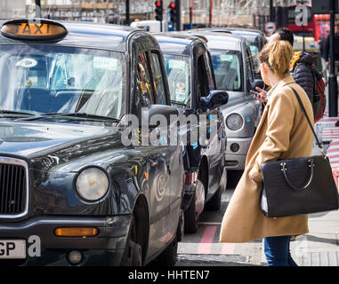 Londra Taxi - London Taxi Black Cabs coda - Una donna attende in corrispondenza di una stazione di taxi a Londra Foto Stock