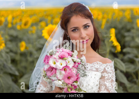 Giovane e bella sposa in posa di un campo di semi di girasole Foto Stock