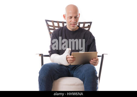 Giovane con un cast sul suo braccio usando un accessibile alle persone portatrici di handicap computer tablet con una mano le funzioni di accessibilità Foto Stock