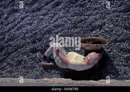 Un vecchio uomo di fumare una sigaretta su una spiaggia in Penzance, Cornwall Foto Stock