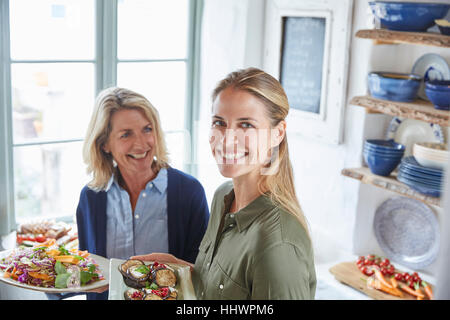 Ritratto sorridente madre e figlia che serve cibo Foto Stock