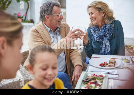 Felice coppia senior tostare calici da bianco al patio pranzo Foto Stock